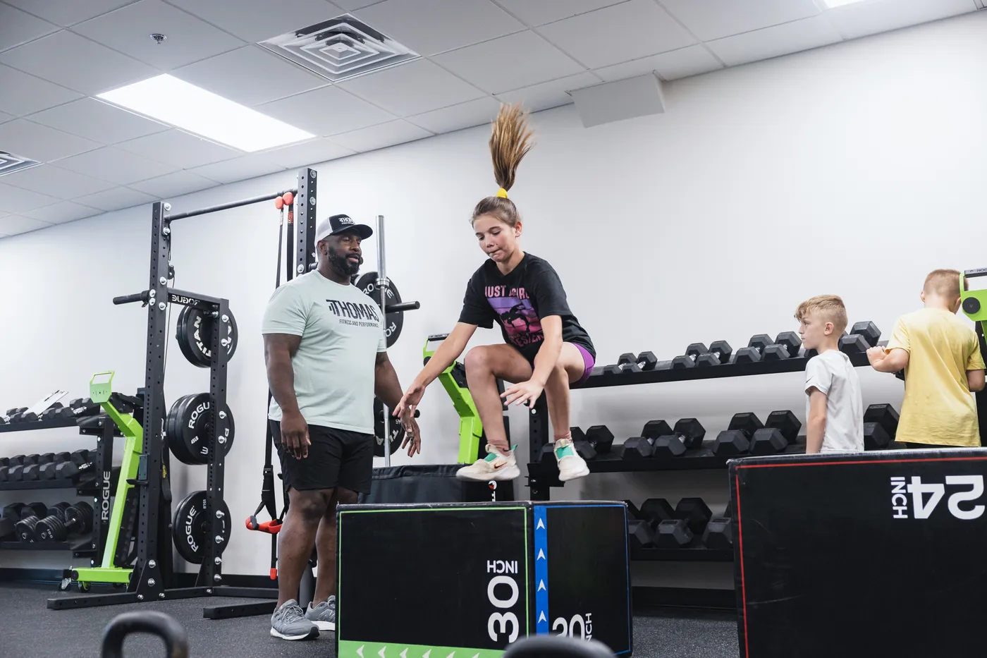 Coach cueing a young athlete through a box jump during an Iron Athlete session